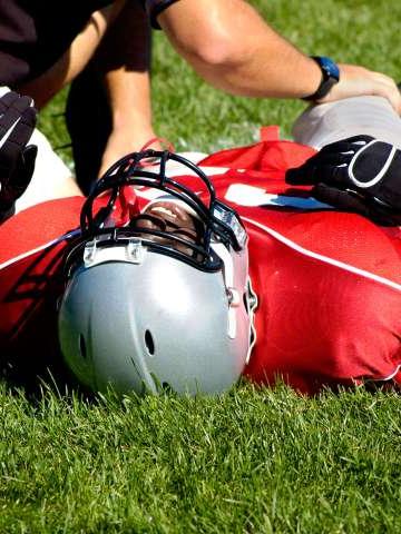 受伤的美式足球运动员躺在草地上